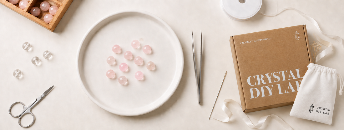 Crystal DIY Lab bracelet-making workspace with pink and clear beads, tools, a branded box, and a storage pouch.